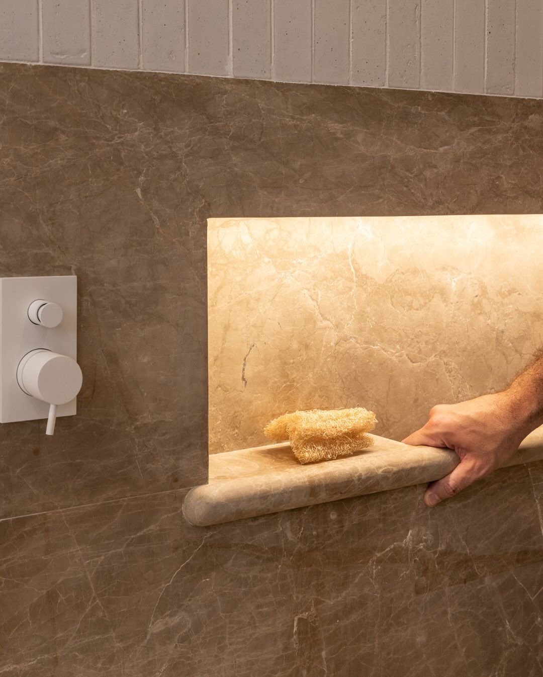 Bathroom detail with a backlit niche in cream marble